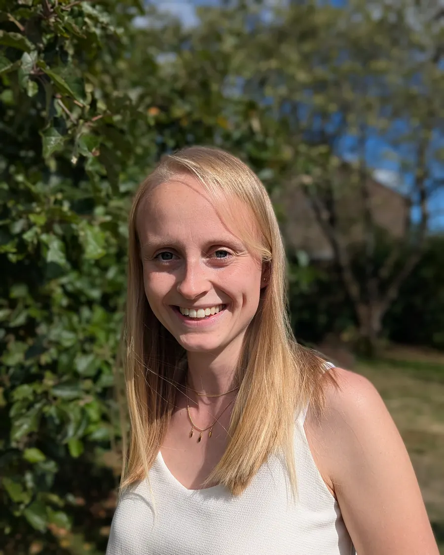Coralie Poncelet, en extérieur, devant une haie