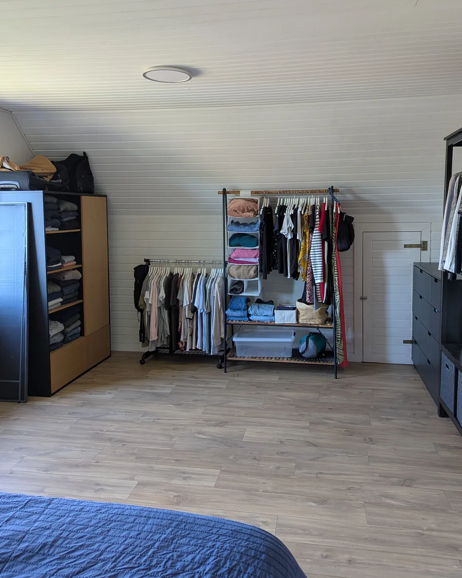 Le même dressing après rangement par une home organiser près de Ciney : portants et meubles le long des murs, parquet dégagé