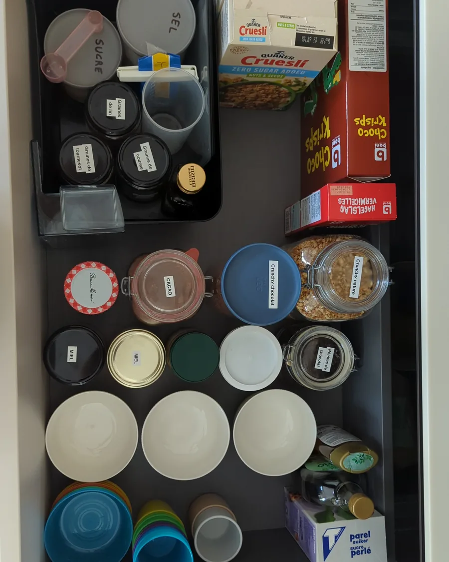 Le même tiroir après rangement par une home organiser près de Ciney : bocaux étiquetés, bols empilés, gobelets de couleur