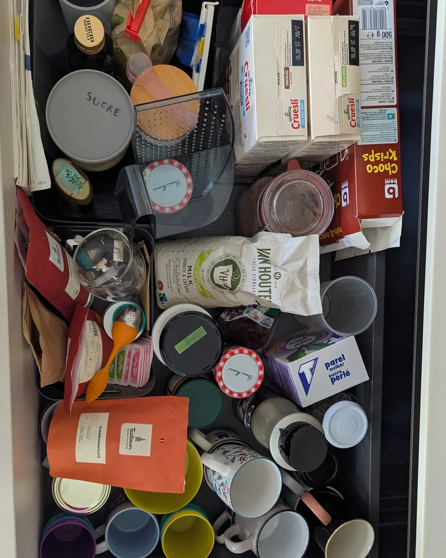 Tiroir de cuisine avant rangement, vu du dessus : céréales, sachets, tasses et boîtes en vrac